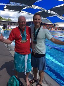 Image shows John and Adam poolside with their medals